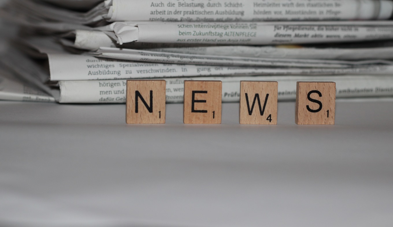 Pila di quotidiani con le lettere della parola news in primo piano