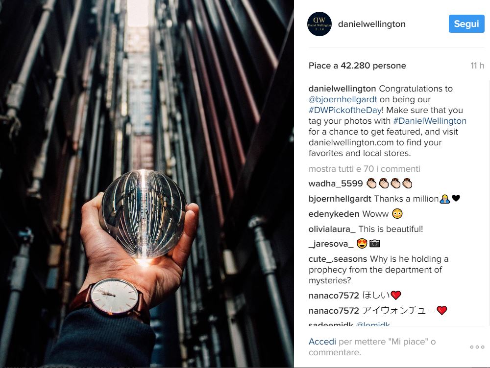 Un orologio Daniel Weelington fotografato su un polso. Una mano tiene una sfera.
