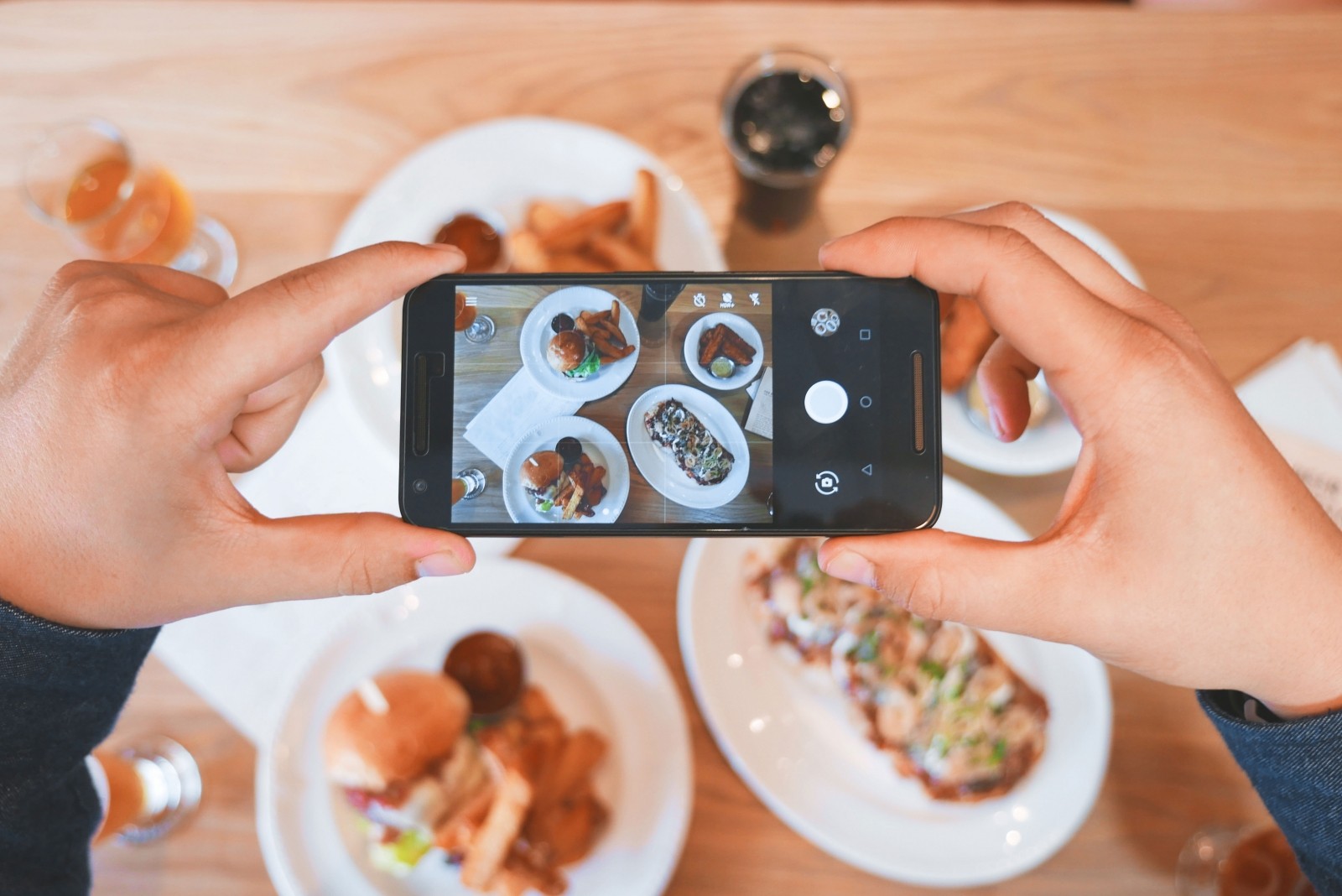 Smartphone che scatta una foto ad una tavola piena di cibi e piatti per condividerla su Instagram