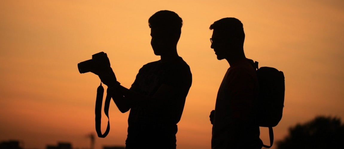 visual content: immagine di due persone con macchina fotografica su sfondo panoramico arancione