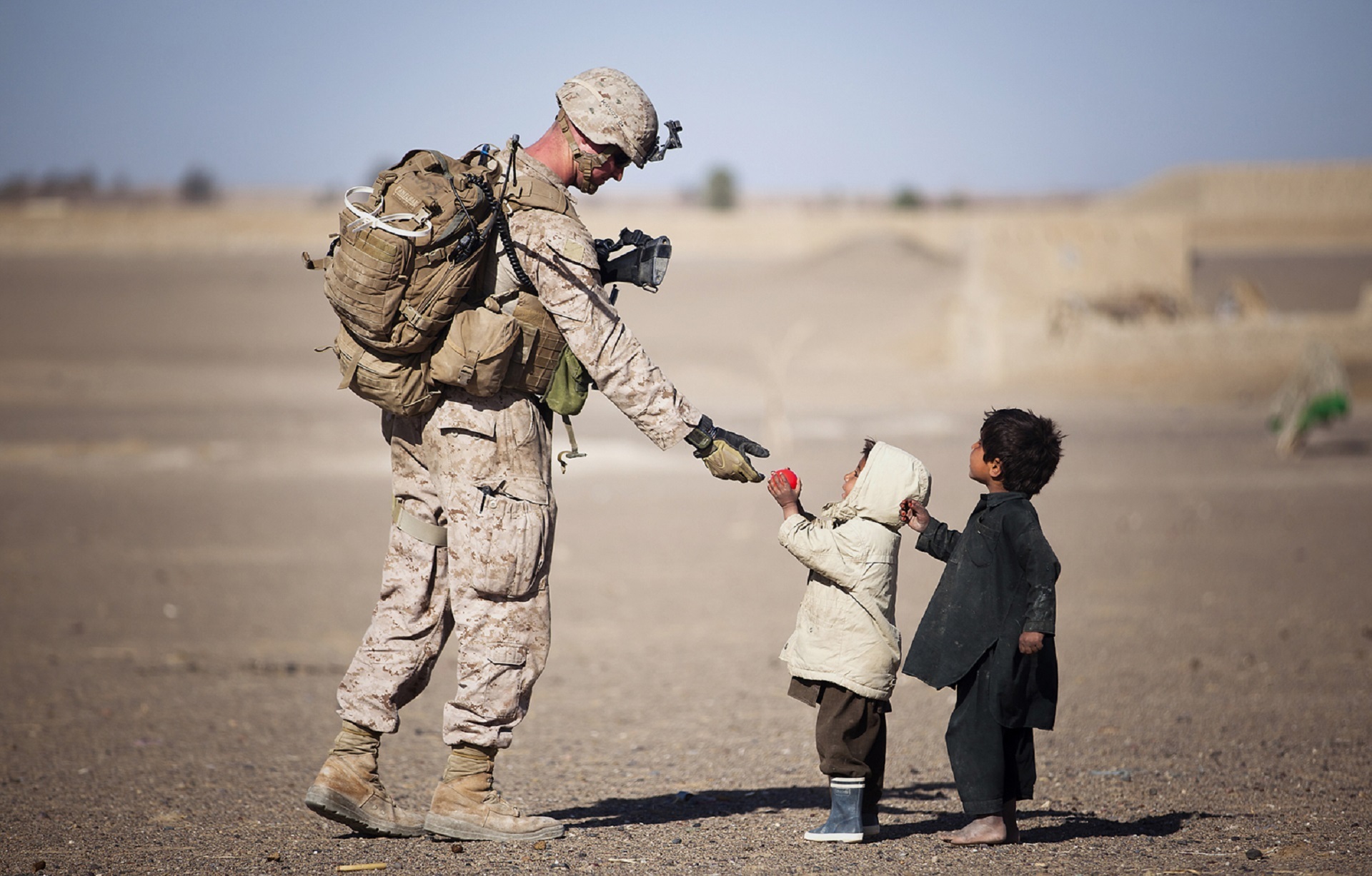 Un soldato dona qualcosa a dei bambini. Questa è una foto che induce alla pre-suasione, che ha molto a che fare con il content marketing